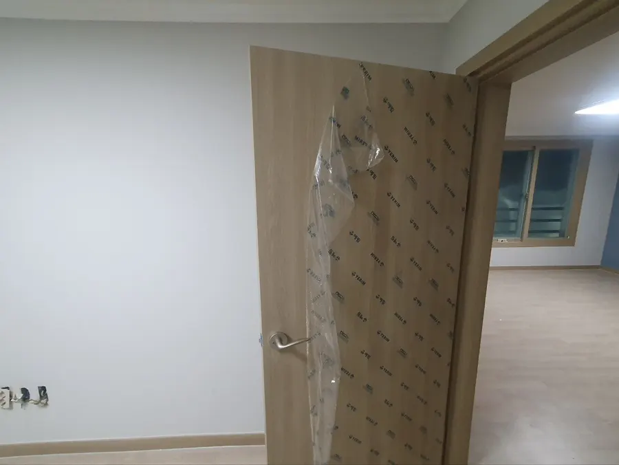 새 방문을 열어 둔 방 입구와 도배를 마친 벽