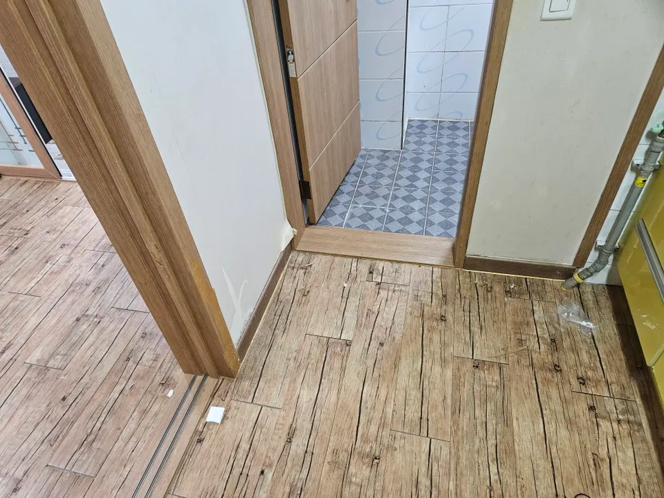 욕실 문 앞 벽 하단에 새 걸레받이를 붙인 모습