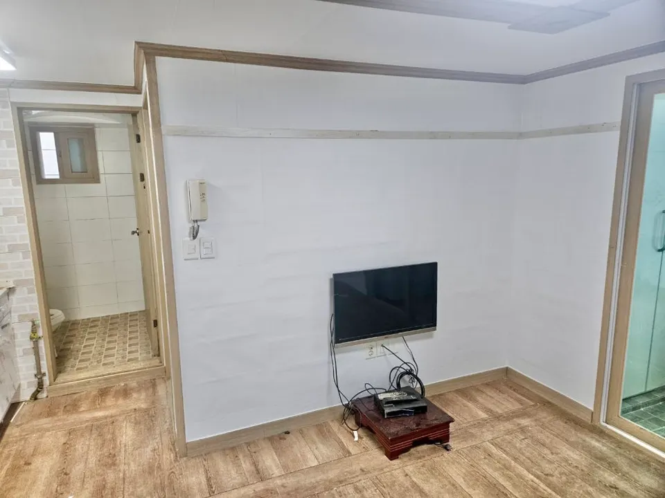 화이트 합지 도배와 천장 몰딩을 마친 거실 벽면
