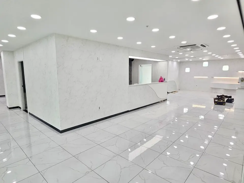 울산 언양 의원 리모델링 후 대리석 무늬 방염필름 벽과 접수대, 밝은 포세린 타일 바닥의 대기 공간