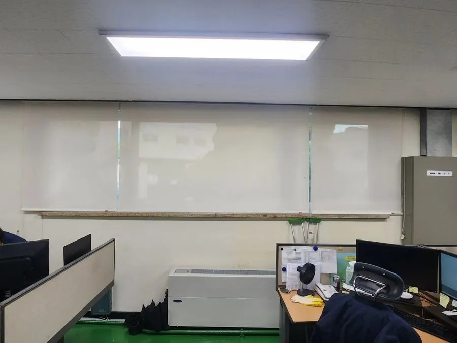 사무 책상 뒤 창 전체에 설치한 썬스크린 롤블라인드