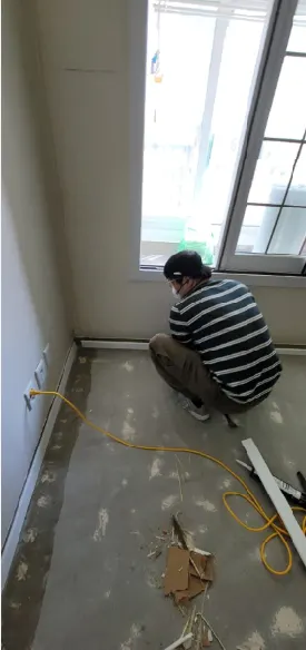 창가 쪽 벽 하단에 새 걸레받이를 붙이는 작업