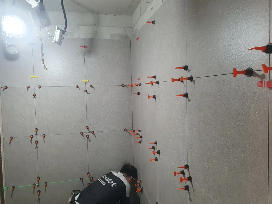 레벨 클립으로 욕실 벽 타일 간격을 맞추는 작업